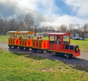 a red and yellow train with people riding on it at Ninemia Stay and Play in Karpenisi