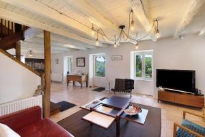 a living room with a couch and a tv at Les Temps Des Sources in Veyrines-de-Domme