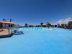 a large swimming pool with blue water on it at Apartamento tranquilo Sun Beach in Caleta De Fuste