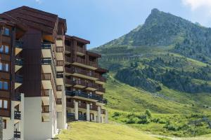 a building on a hill with a mountain in the background at Résidence Pierre & Vacances Les Gémeaux in Belle Plagne