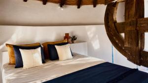 a bedroom with a bed with blue and white pillows at The Windmill Serifos in Serifos Chora