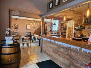 a restaurant with a bar and a table with chairs at Hotel Les Vieux Acacias in Queyrac