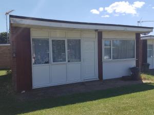 a garage with white doors and windows in a yard at SHORTIEs STAYS in Hemsby