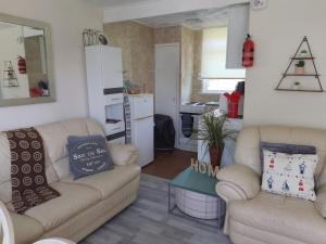 a living room with two couches and a kitchen at SHORTIEs STAYS in Hemsby