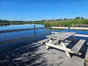a picnic table on a dock next to a lake at Agroturystyka Golubie in Ełk