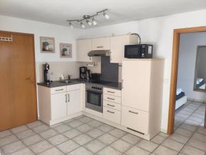 a kitchen with white cabinets and a microwave at Ferienwohnung am Trillenbühl in Salem +13 photos