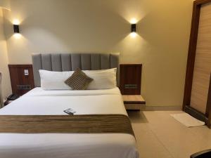 a bedroom with a large bed with white sheets and pillows at Hotel Golden Crown in Mumbai
