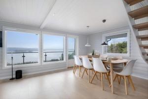 a dining room with a table and chairs and windows at The Green Bay in Sandnes