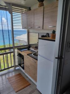 a kitchen with white appliances and a large window at Lady laying in Le Diamant