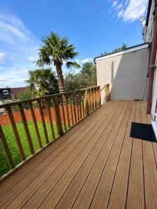 a wooden deck with a palm tree in the background at Newly Refurbished House in Norwood