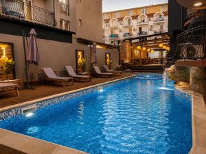 a swimming pool in a hotel with chairs and a building at Adeti Residence in Nesebar