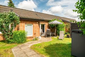 a brick house with an umbrella and a table and chairs at Blumenhaus mit Terrasse in Waren
