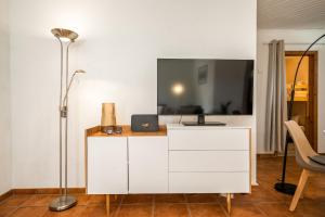 a white dresser with a tv on top of it at Blumenhaus mit Terrasse in Waren