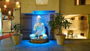 a statue of a buddha in a room with two plants at Hotel Heritage Grand in Thane