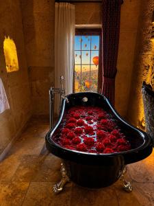 a bath tub filled with red roses in a bathroom at Hira Cave Hotel in Göreme