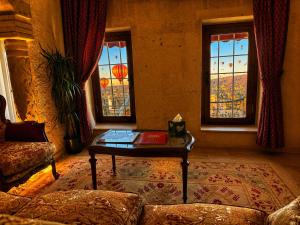 a living room with a table and two windows at Hira Cave Hotel in Göreme