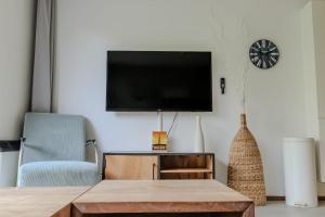 a living room with a tv and a table and a chair at Appartement De Noordkaap in Hollum