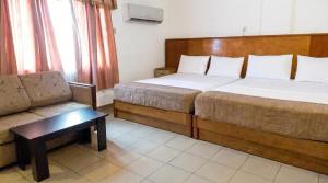 ein Hotelzimmer mit zwei Betten und einer Couch in der Unterkunft Embel Hotel in Port Harcourt