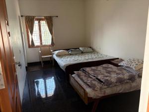 a room with three beds in it with a window at Senthur Bavanam in Udumalaippettai