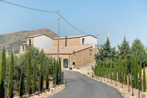 a road in front of a building with a bunch of trees at Sikania Agrirelais in Caccamo