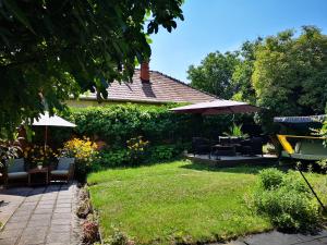 a garden with chairs and tables and an umbrella at Villa-Hotel Escala in Cluj-Napoca