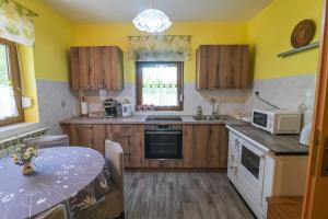 a kitchen with wooden cabinets and a table and a microwave at Apartma pod Rožem in Soča