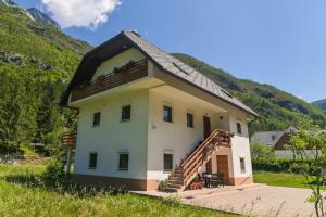a house with a staircase in front of a mountain at Apartma pod Rožem in Soča