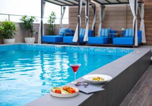 a table with a drink and food next to a swimming pool at Rhythm Gurugram, Hotel & Suites, Sohna Road, Sector 68 in Gurgaon