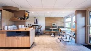 a restaurant with a counter and chairs and tables at Premiere Classe Orleans Nord - Saran in Saran