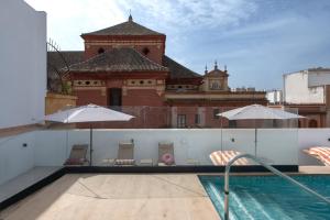a swimming pool with chairs and umbrellas on a building at Líbere Seville Triana in Seville +92 photos