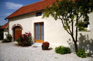 a small white house with a red door and flowers at Les prés saint jean in Champigny-sur-Aube