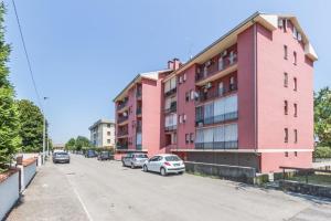 a pink building with cars parked in a parking lot at Piccolo paradiso in Viadana