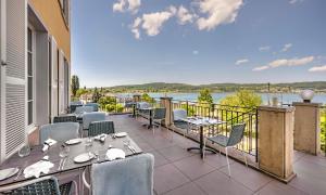 a balcony with tables and chairs and a view of the water at VILLA LINDE Seehotel in Bodman-Ludwigshafen