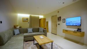 a living room with a couch and a flat screen tv at منتجع اغصان الشفا in Ash Shafa