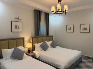 two beds in a bedroom with a chandelier at Luangaloun Guesthouse in Luang Prabang