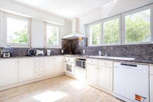 a white kitchen with white cabinets and windows at La parenthèse Océane -Avec piscine in Concarneau