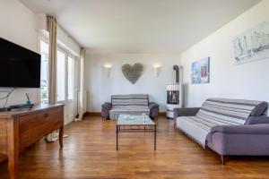 a living room with two couches and a flat screen tv at La parenthèse Océane -Avec piscine in Concarneau