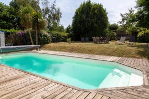 a swimming pool with a wooden deck and a yard at La parenthèse Océane -Avec piscine in Concarneau