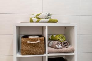 a white shelf with towels and a basket on it at Weinbergschnecke Ferienwohnung in Efringen-Kirchen +12 photos