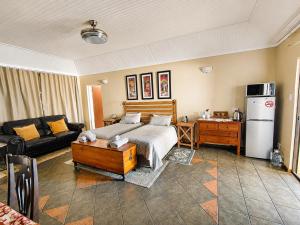 a bedroom with a bed and a couch and a refrigerator at WHY NOT GUESTHOUSE in Bothaville