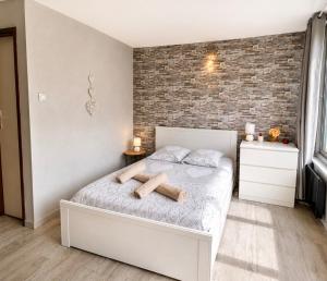a bedroom with a white bed and a brick wall at Petit Nid Nature Et Douceurs in Turckheim