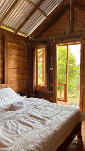 a large bed in a wooden room with a window at Kuna GlampCamp in Gitgit
