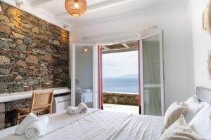 a bedroom with a bed with a view of the ocean at Nalo Suites & Villas in Kithnos +57 photos