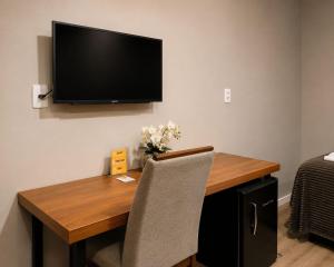 a wooden table with a television on a wall at Hotelcity in Brusque