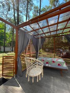 a swing in a pergola with a bed of flowers at W sosnowym lesie 2 in Lubniewice
