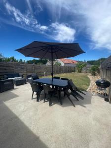 a table and chairs with an umbrella on a patio at gîte Théalys- proche Puy du Fou in La Petite-Boissière