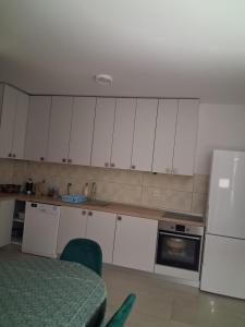 eine Küche mit weißen Schränken, einem Tisch und einem Kühlschrank in der Unterkunft Radoš in Igalo