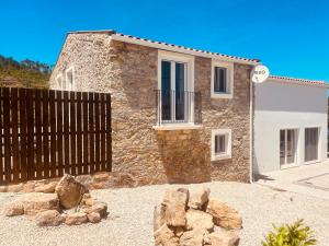 a stone house with a fence in front of it at Casa Borboleta in Chão de Lamas