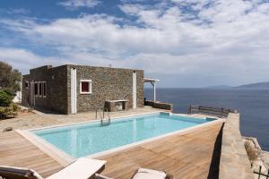 a house with a swimming pool next to the ocean at Nalo Suites & Villas in Kithnos