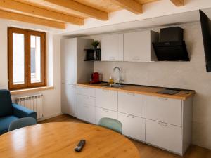 a kitchen with white cabinets and a wooden table at Clelia appartamento 6 posti vicino le piste da sci in Temù
